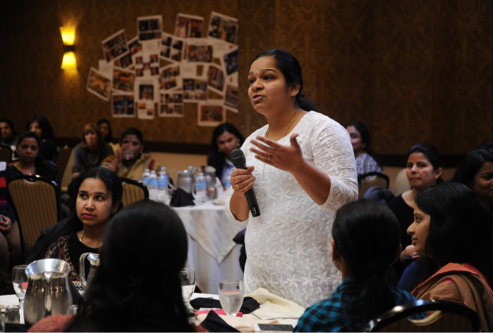 A woman stood speaking at a round table discussion.